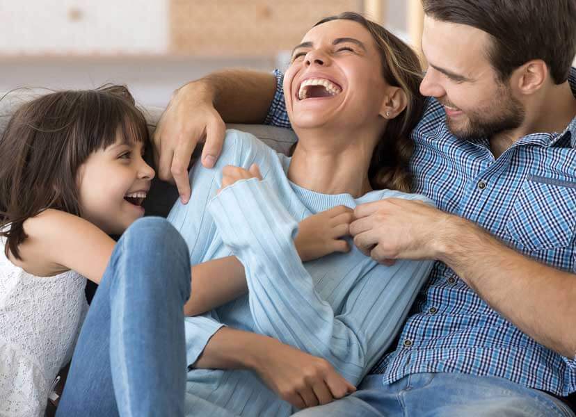 A happy couple sitting on the couch with their child